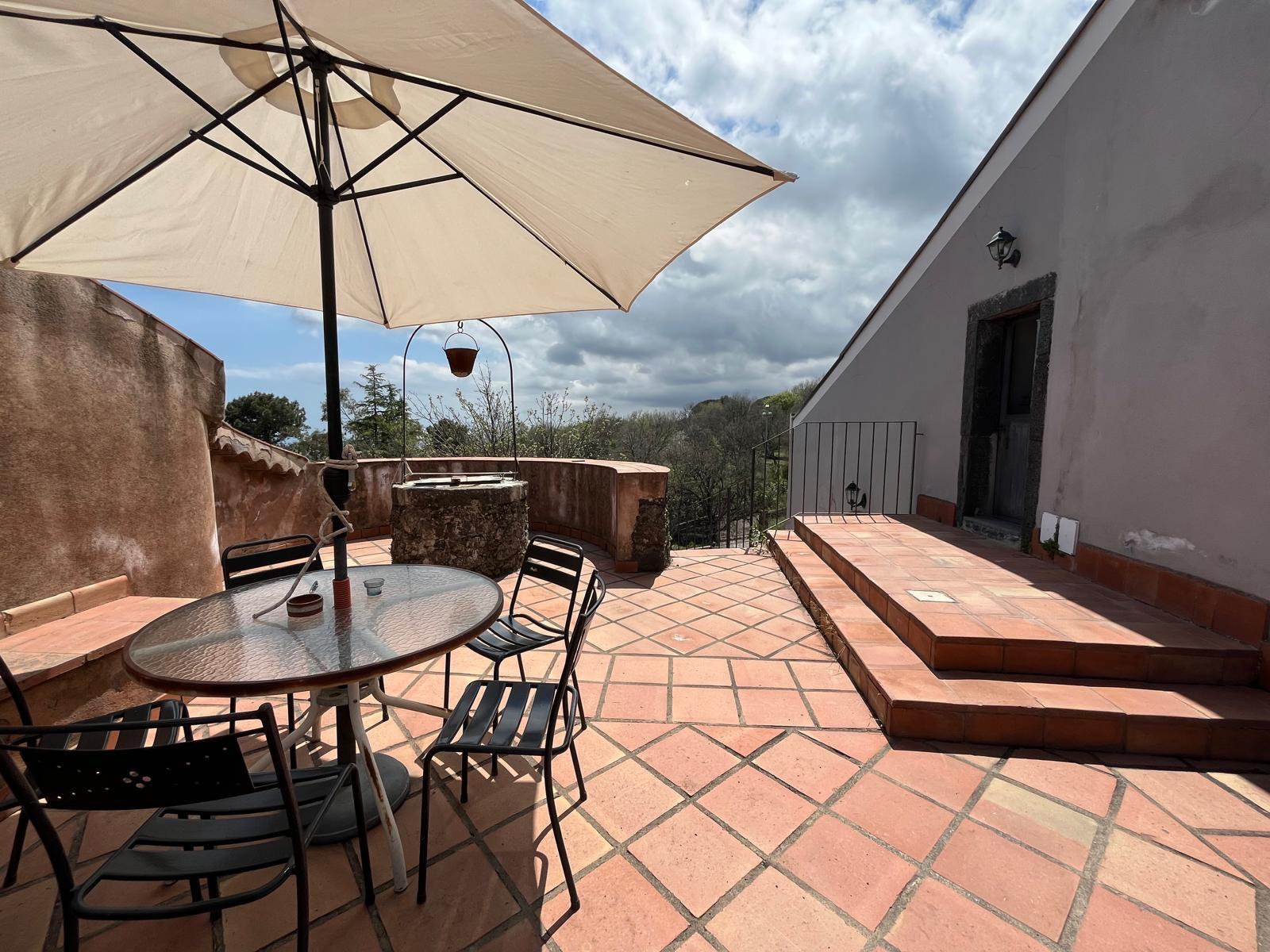 Terrazza panoramica con ombrellone e antico pozzo — Etna 1928 Country House
